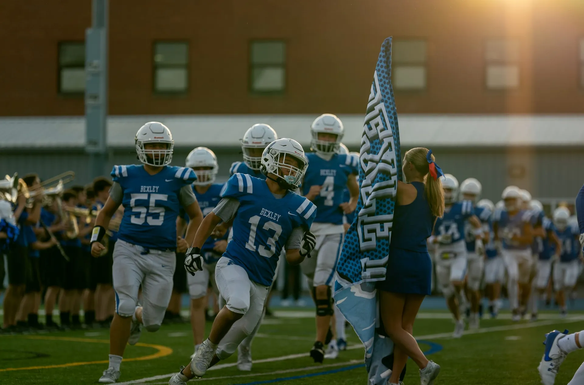 The Bexley football team taking the field past the flag line