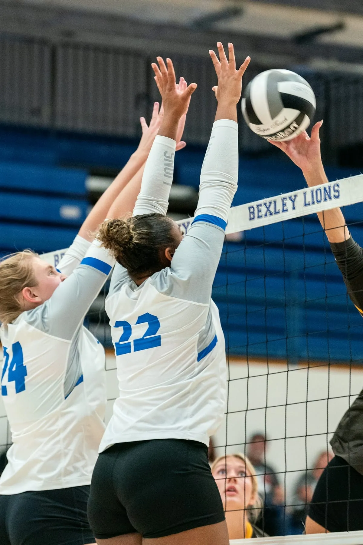 Two Bexley volleyball players rising for a block at the net