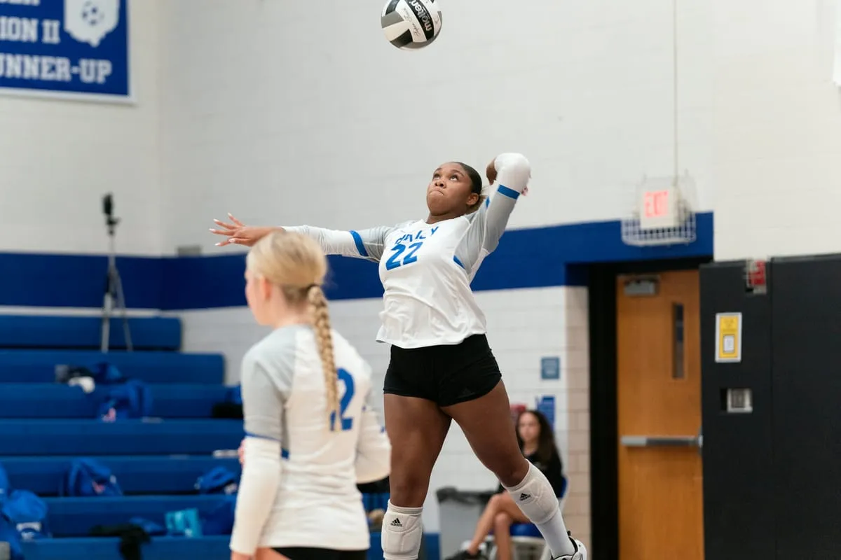 A Bexley volleyball player serving inside the gymnasium
