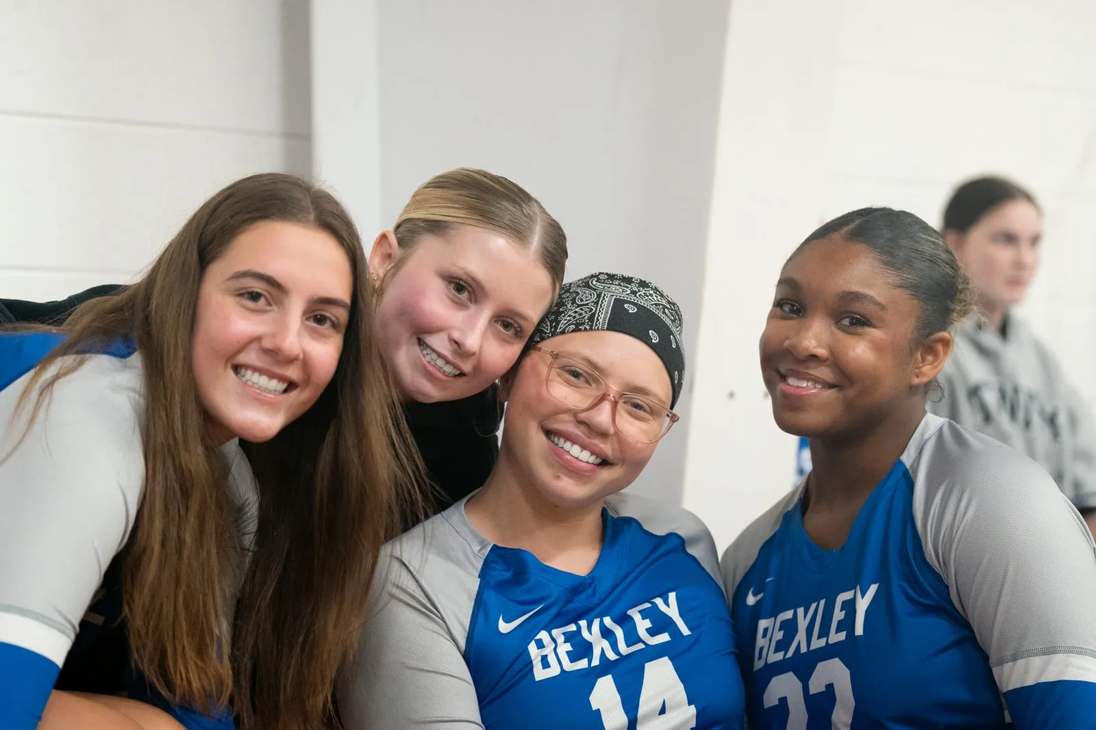 Four Bexley volleyball teammates smiling together courtside